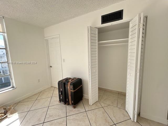 unfurnished bedroom featuring a textured ceiling, a closet, and multiple windows