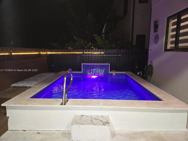 pool at night featuring pool water feature