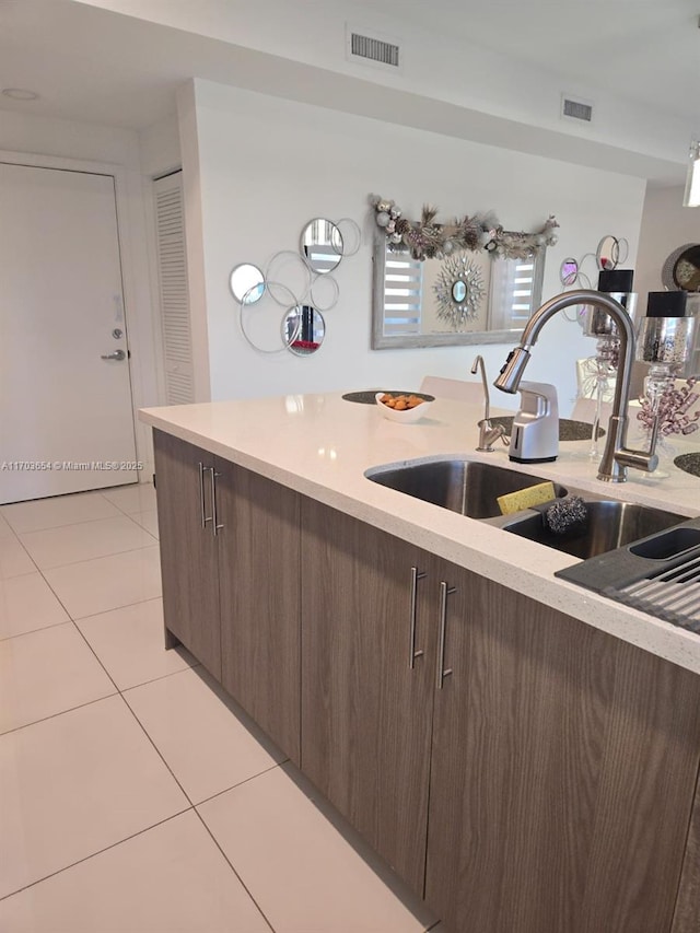 kitchen featuring sink, light tile patterned floors, and dark brown cabinetry