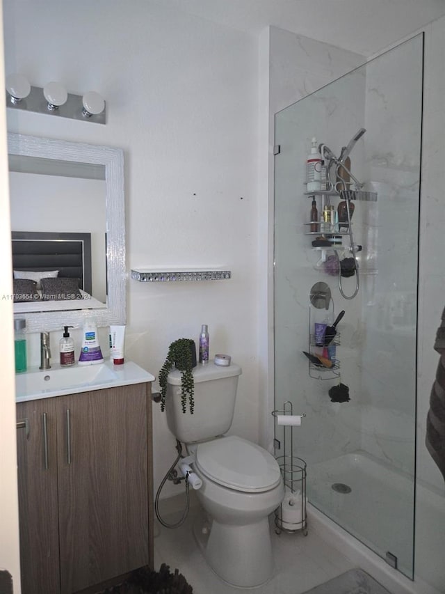 bathroom with tile patterned floors, vanity, a shower with shower door, and toilet