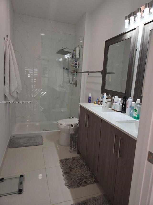 bathroom with tile patterned flooring, vanity, tiled shower, and toilet