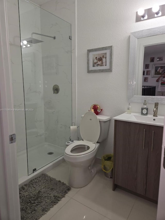 bathroom featuring tile patterned floors, vanity, toilet, and a tile shower