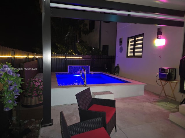 pool at twilight with pool water feature and a bowling alley