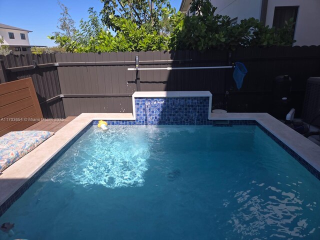 view of swimming pool featuring pool water feature and central AC unit