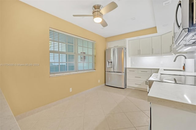 kitchen featuring ceiling fan, sink, light tile patterned floors, white cabinets, and appliances with stainless steel finishes