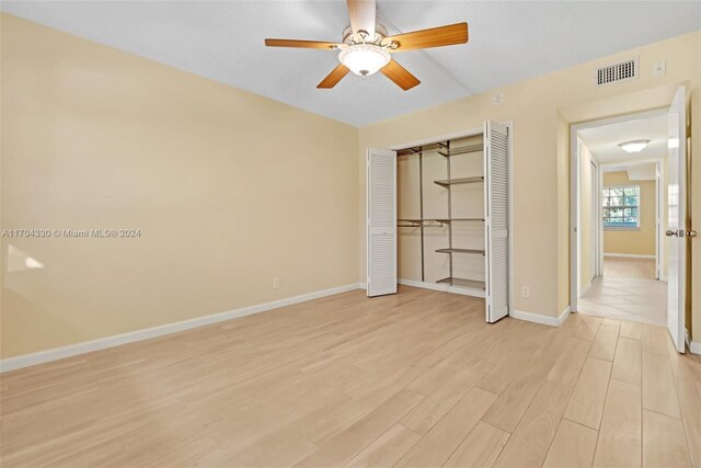 unfurnished bedroom with a closet, light hardwood / wood-style flooring, and ceiling fan