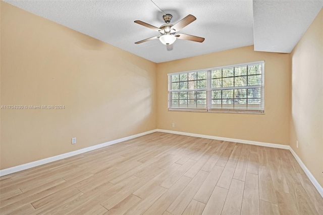 empty room with ceiling fan, light hardwood / wood-style floors, and a textured ceiling