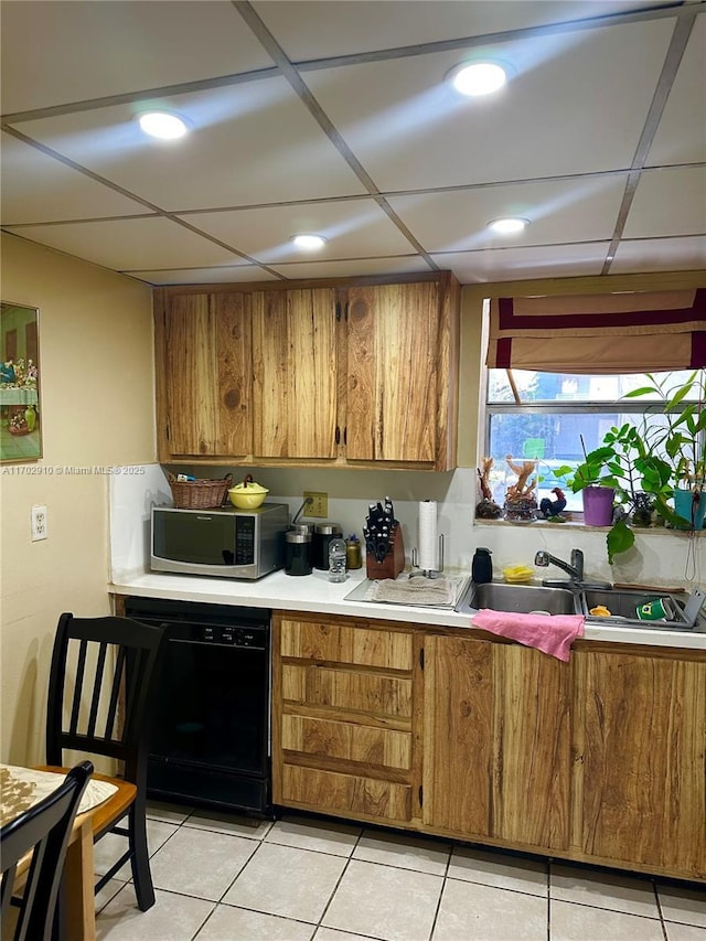 kitchen featuring stainless steel microwave, dishwasher, brown cabinets, a sink, and light countertops