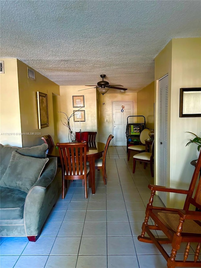 tiled dining space with a ceiling fan and a textured ceiling