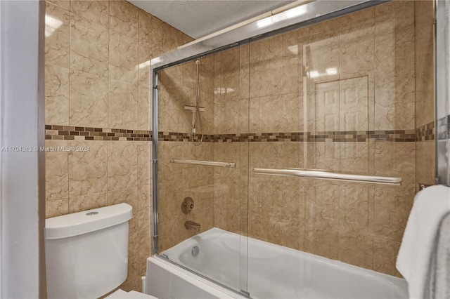 bathroom featuring toilet, enclosed tub / shower combo, a textured ceiling, and tile walls