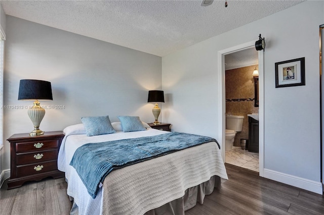 bedroom with ensuite bathroom, dark hardwood / wood-style flooring, and a textured ceiling