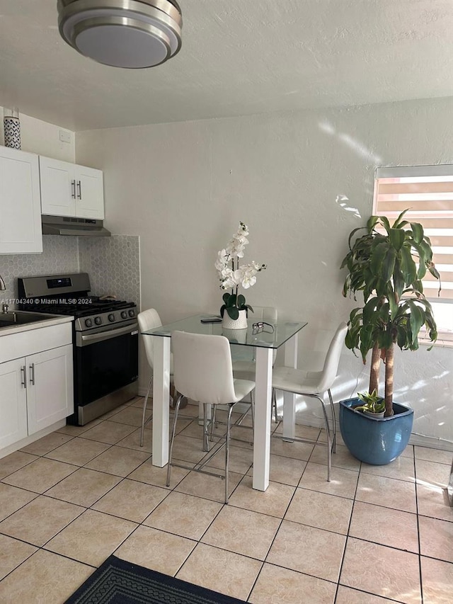 kitchen featuring white cabinetry, sink, light tile patterned floors, and stainless steel range with gas stovetop