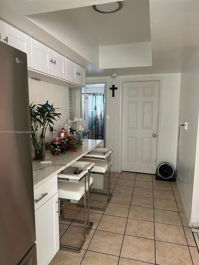 kitchen featuring light tile patterned flooring, white cabinetry, and stainless steel refrigerator