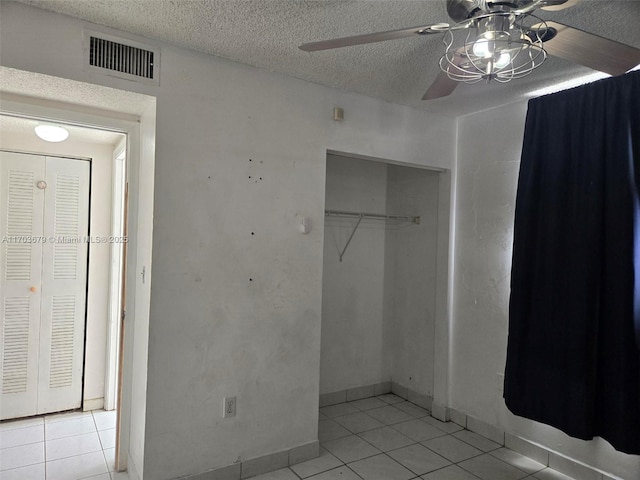 unfurnished bedroom with a textured ceiling, a closet, ceiling fan, and light tile patterned flooring