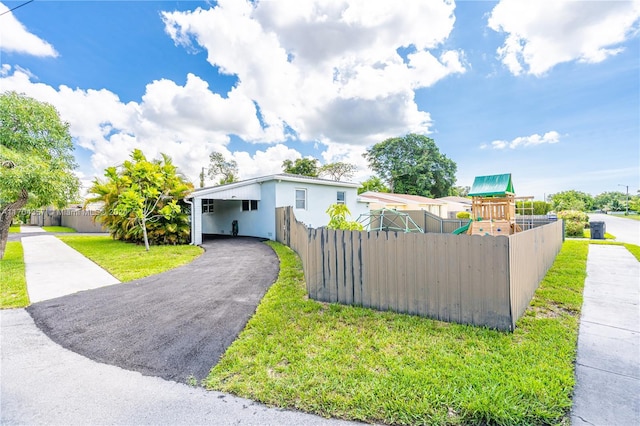 view of front of property featuring a carport, a playground, and a front yard