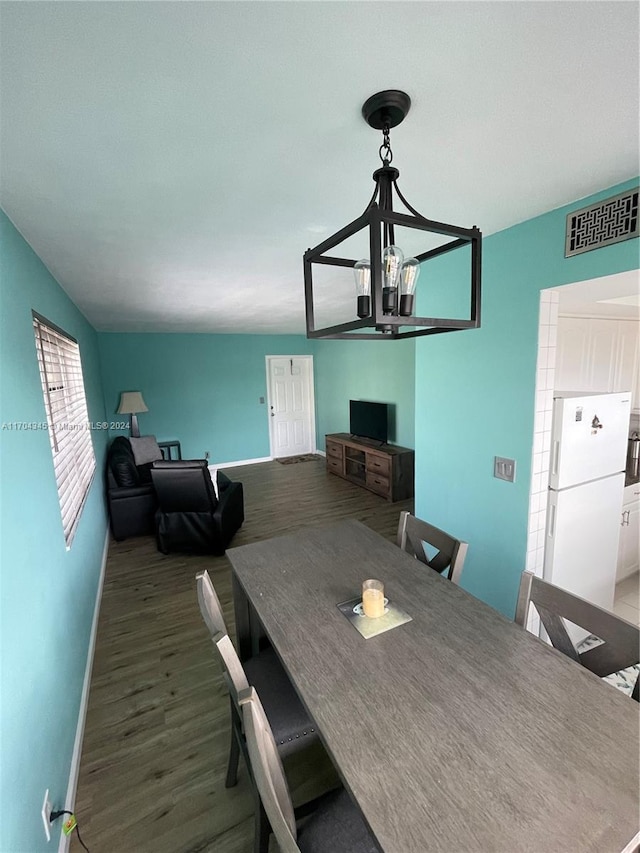 unfurnished dining area with dark hardwood / wood-style floors, a chandelier, and vaulted ceiling