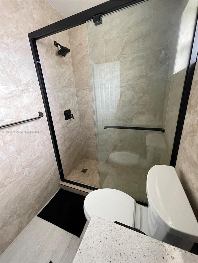 bathroom with toilet, walk in shower, and tile walls