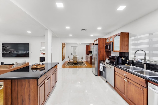 kitchen with appliances with stainless steel finishes, light wood-type flooring, a kitchen island, and sink