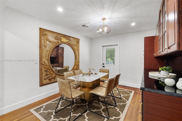 dining area with a notable chandelier, dark hardwood / wood-style flooring, and a textured ceiling