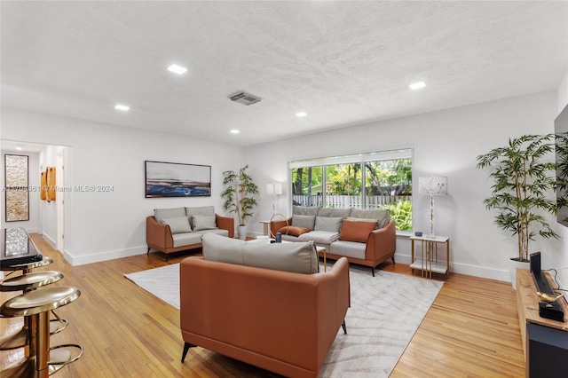 living room with a textured ceiling and light hardwood / wood-style floors