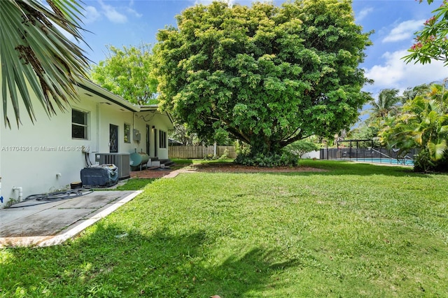 view of yard with cooling unit, a fenced in pool, and a patio