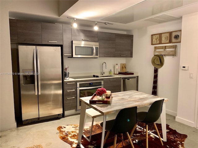 kitchen with a kitchen bar, sink, appliances with stainless steel finishes, and track lighting