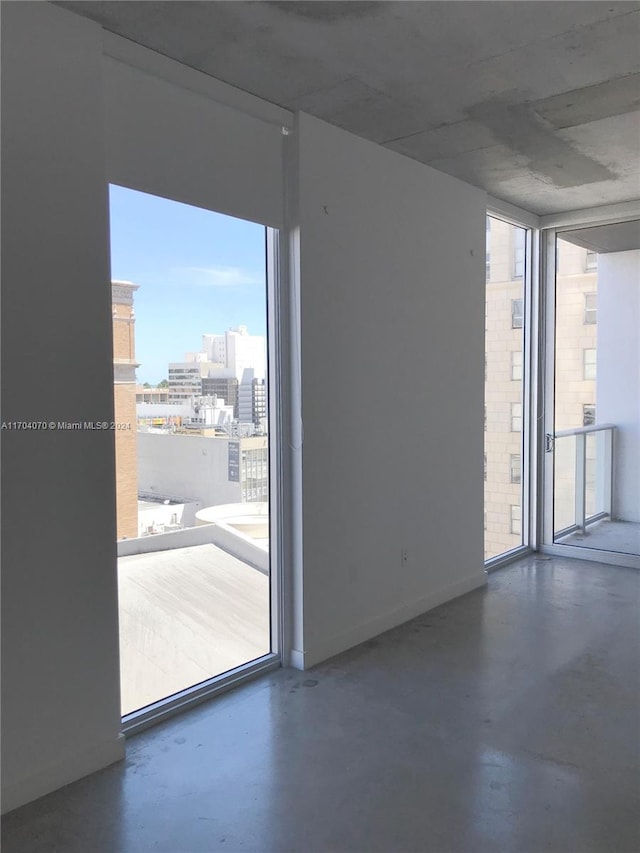 unfurnished room featuring floor to ceiling windows, plenty of natural light, and concrete floors