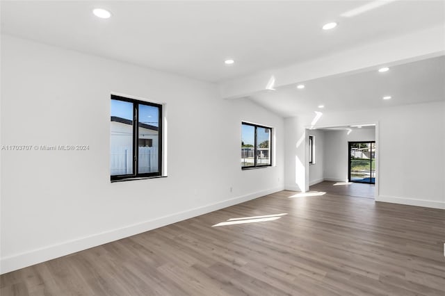 unfurnished room featuring hardwood / wood-style flooring and lofted ceiling with beams