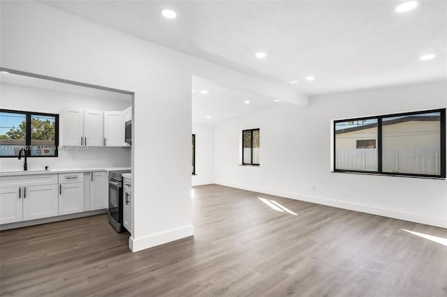 kitchen featuring appliances with stainless steel finishes, sink, vaulted ceiling with beams, dark hardwood / wood-style floors, and white cabinetry