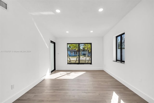 spare room with plenty of natural light and light hardwood / wood-style flooring