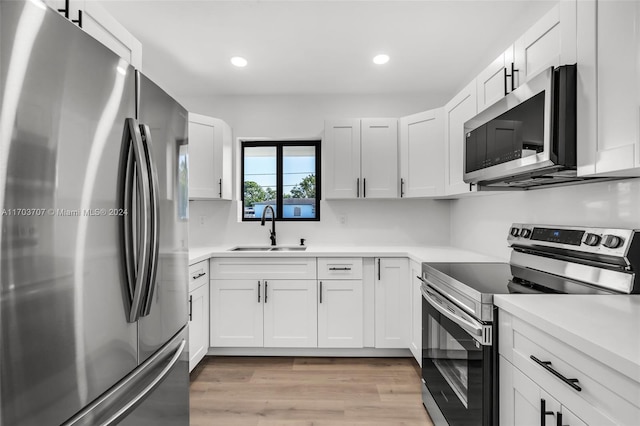 kitchen featuring sink, white cabinets, light wood-type flooring, and appliances with stainless steel finishes