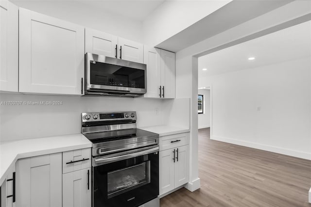 kitchen with white cabinets, light hardwood / wood-style floors, and appliances with stainless steel finishes