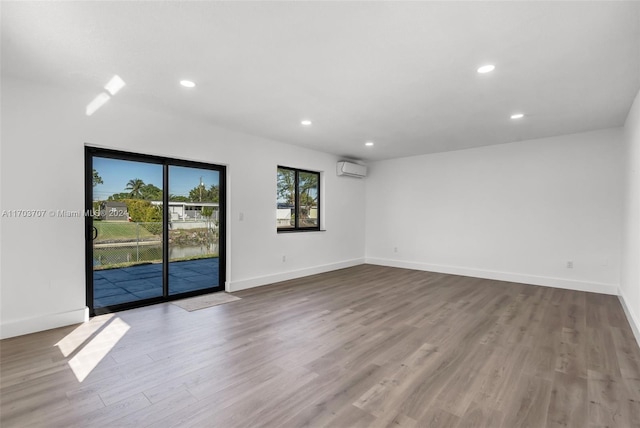 empty room featuring a wall mounted air conditioner and light hardwood / wood-style flooring