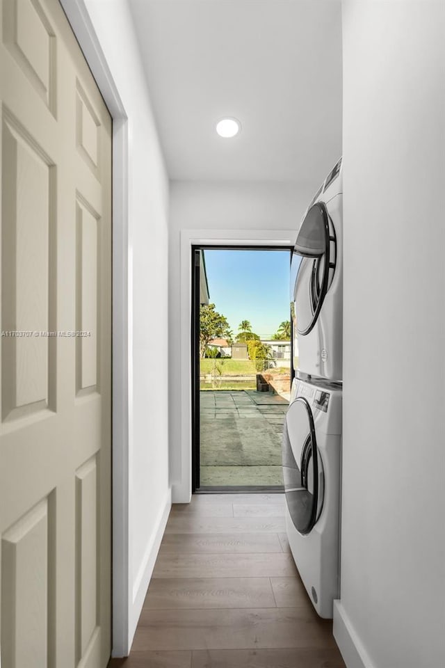 laundry room with hardwood / wood-style floors and stacked washer / dryer