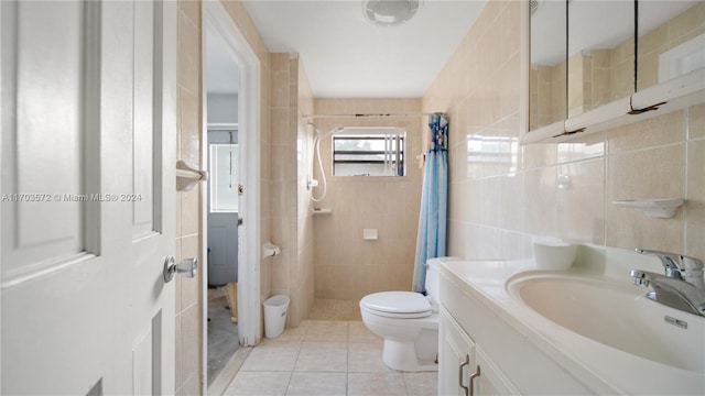 bathroom with toilet, vanity, tile patterned floors, and tile walls