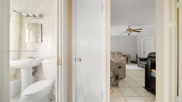 bathroom featuring toilet, tile patterned floors, ceiling fan, and tile walls