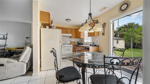 kitchen with light tile patterned floors, white range, hanging light fixtures, and a notable chandelier