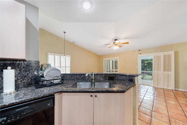 kitchen with dishwasher, sink, vaulted ceiling, dark stone countertops, and plenty of natural light