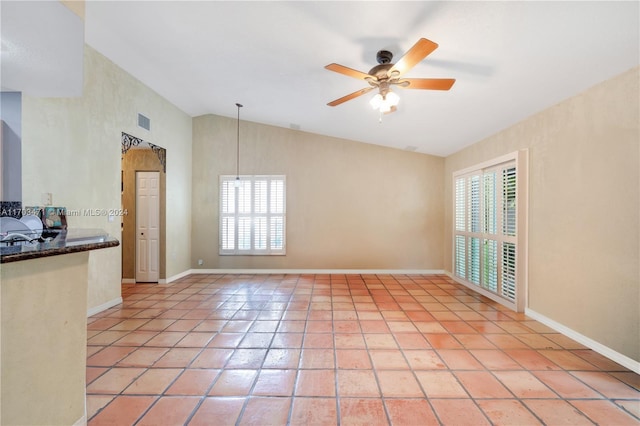 tiled empty room featuring ceiling fan and lofted ceiling