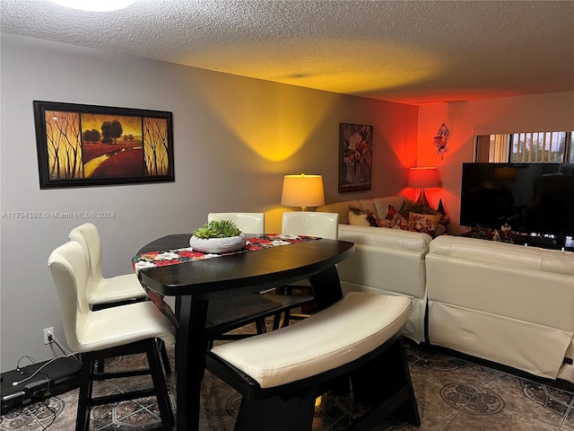 dining space featuring a textured ceiling and dark tile patterned flooring