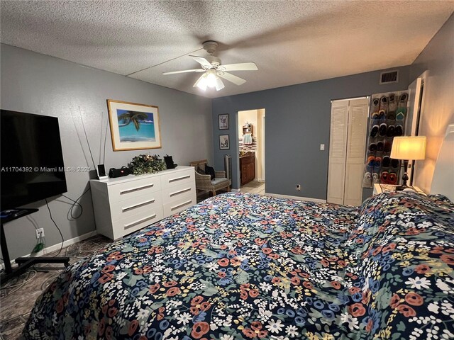 bedroom with a textured ceiling, ensuite bath, and ceiling fan