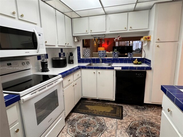 kitchen with tile countertops, white cabinetry, white appliances, and sink