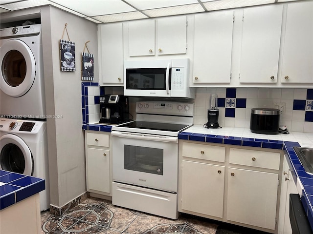 kitchen featuring white appliances, tile counters, and stacked washer / drying machine