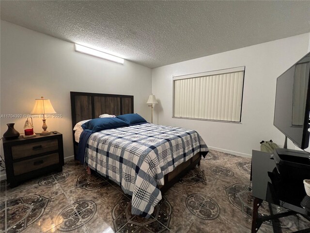 bedroom with a textured ceiling and dark tile patterned flooring