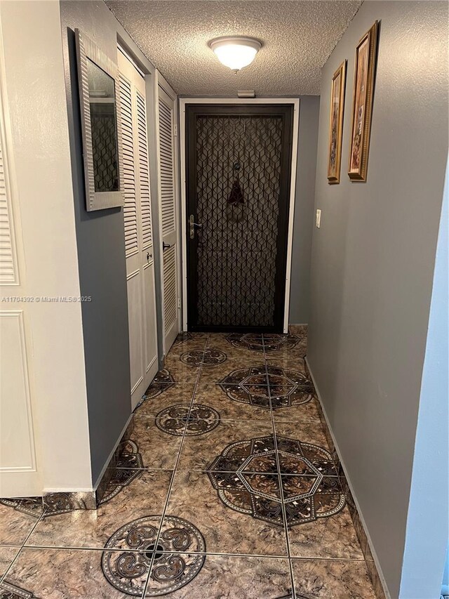 corridor featuring a textured ceiling and dark tile patterned floors