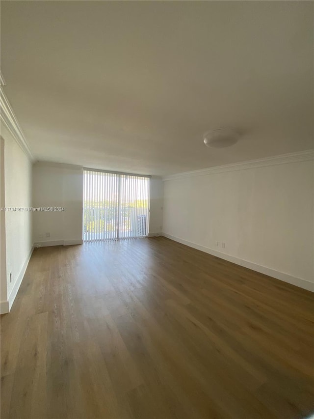 empty room with hardwood / wood-style flooring and crown molding