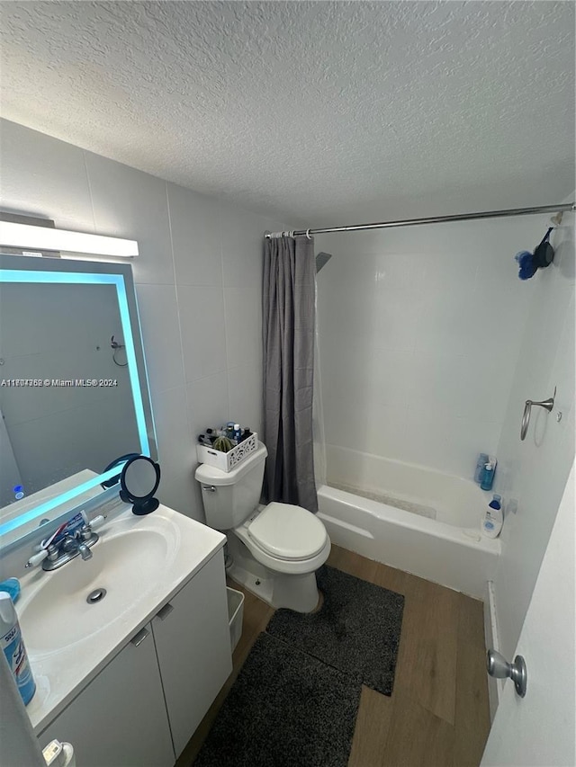 full bathroom featuring shower / bath combo, hardwood / wood-style floors, a textured ceiling, toilet, and vanity