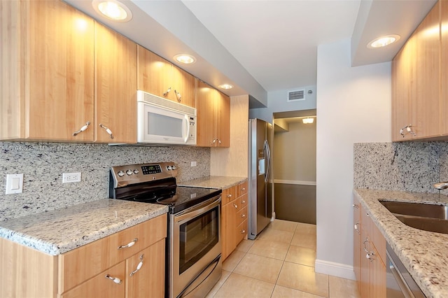 kitchen featuring decorative backsplash, light stone countertops, stainless steel appliances, and light tile patterned floors