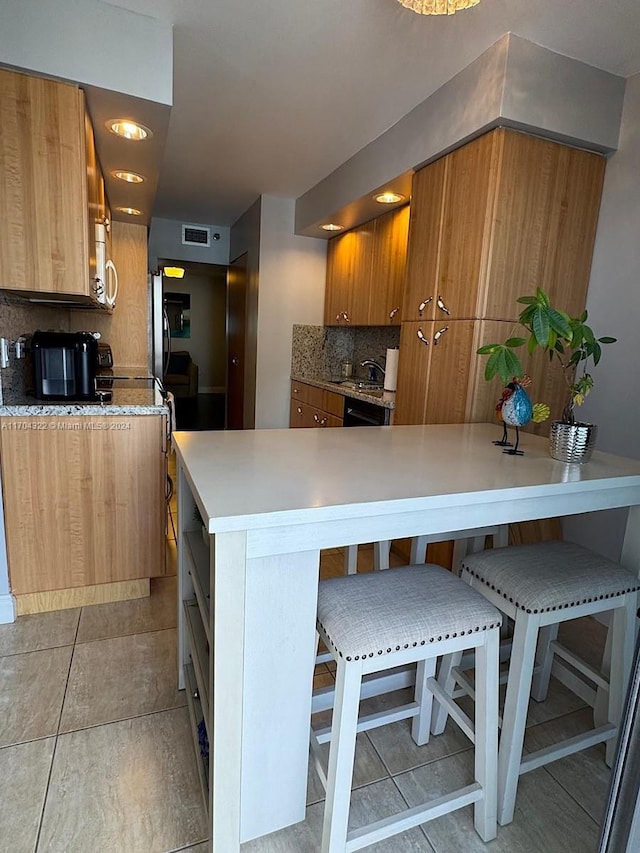 kitchen featuring kitchen peninsula, tasteful backsplash, sink, black dishwasher, and a breakfast bar area