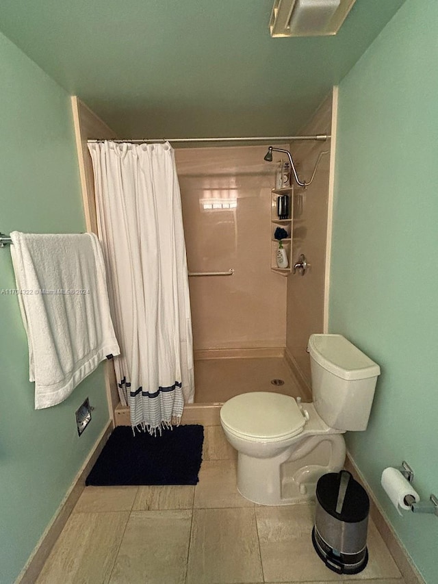 bathroom featuring a shower with shower curtain, toilet, and tile patterned floors